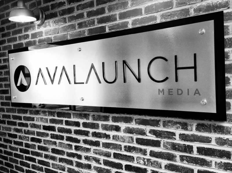 Black and white image featuring the front office Avalaunch Media wall.